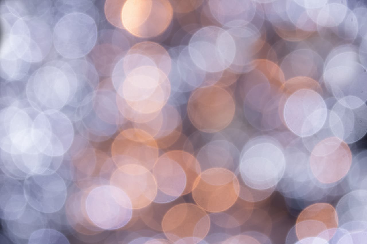 A soft-focus abstract image featuring circular bokeh lights in warm and cool tones.